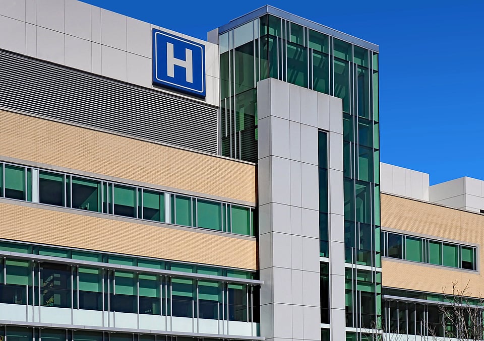 The exterior view of a hospital building with a b "H" on the side.