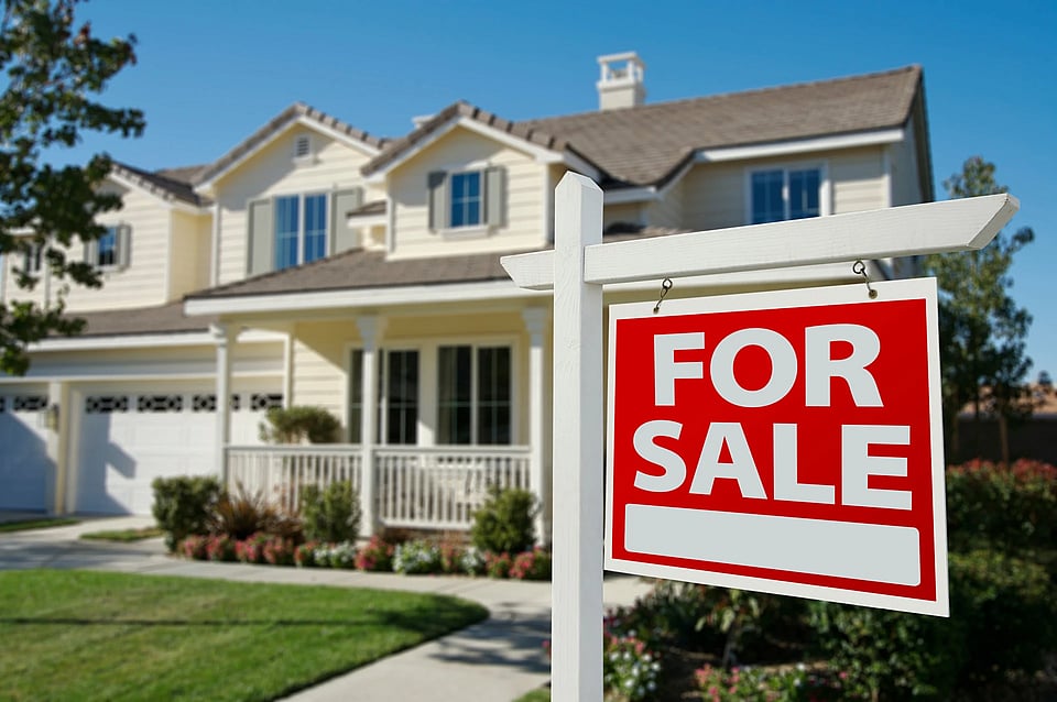 A house with a For Sale sign in front of it.