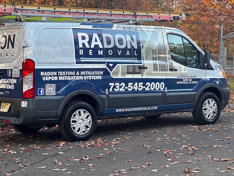 The van for Radon Removal parked with leaves around it.