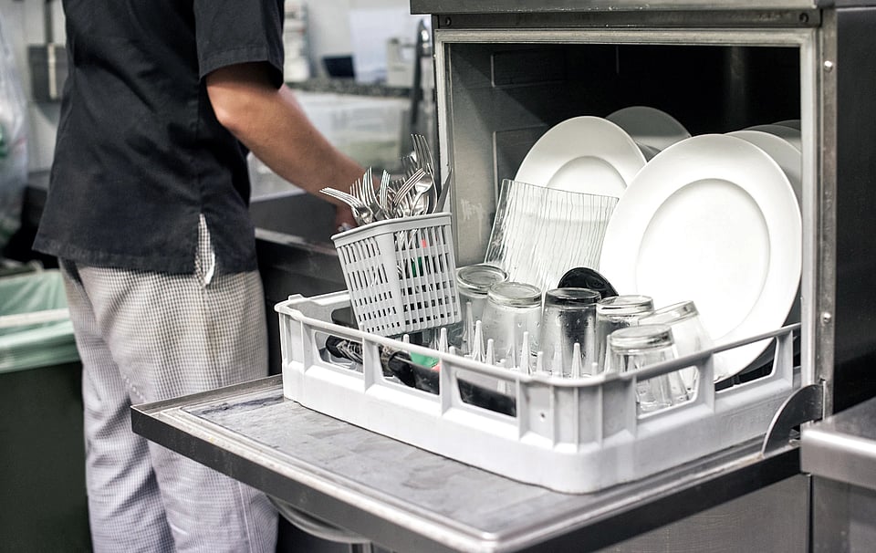 Adobe Stock image of a dishwasher in an industrial kitchen.