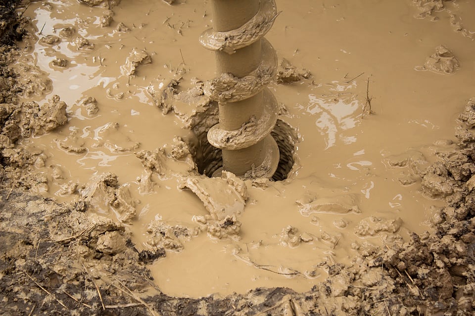 Adobe Stock image of digging a hole for a well in a muddy area.