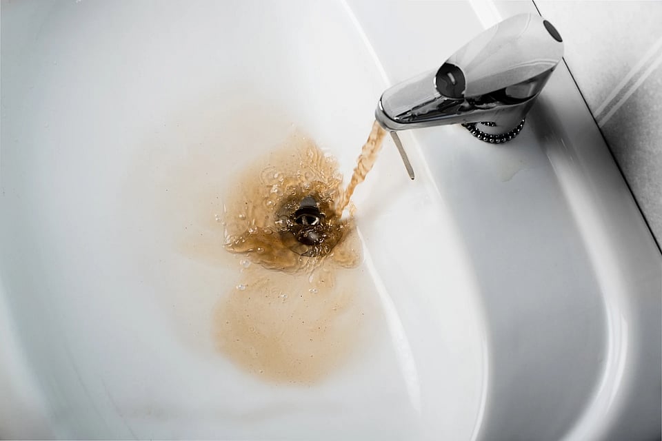 Adobe Stock image of red rusty water coming out of a tap.
