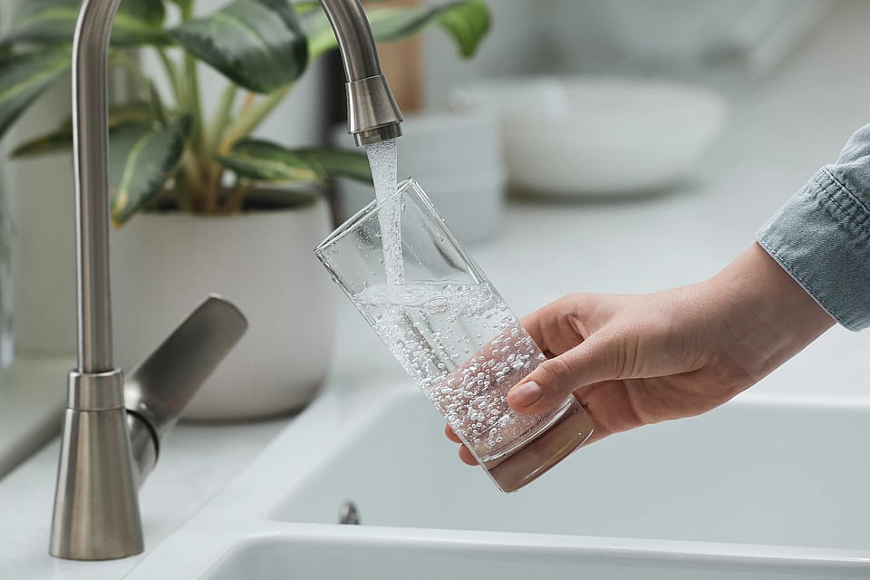 Adobe Stock image of someone filling a glass of crystal clear water from the sink.