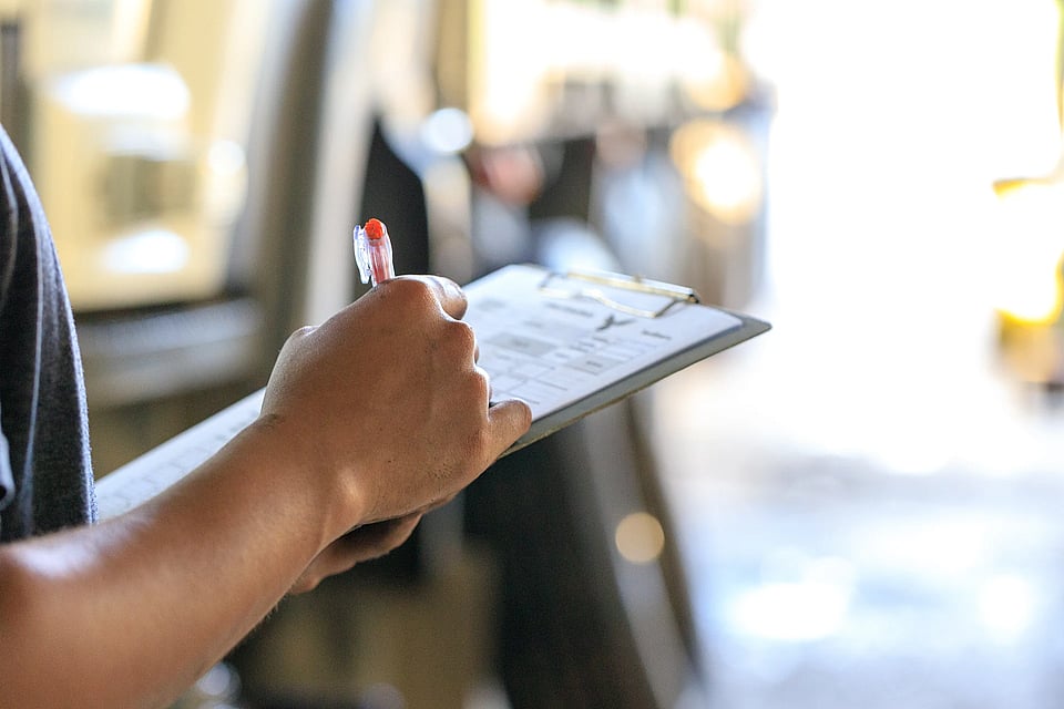 Adobe Stock image of someone writing on a clipboard with a pen.