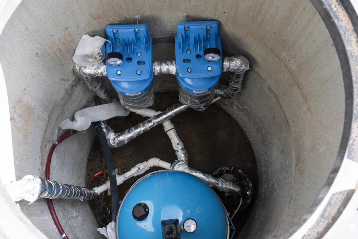 Adobe Stock image of well pumps inside of a concrete well.