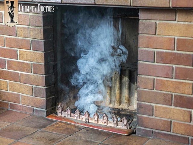 A fireplace filling up with smoke inside a home