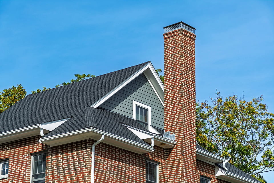 Abobe Stock image of a tall masonry chimney with a metal cap.