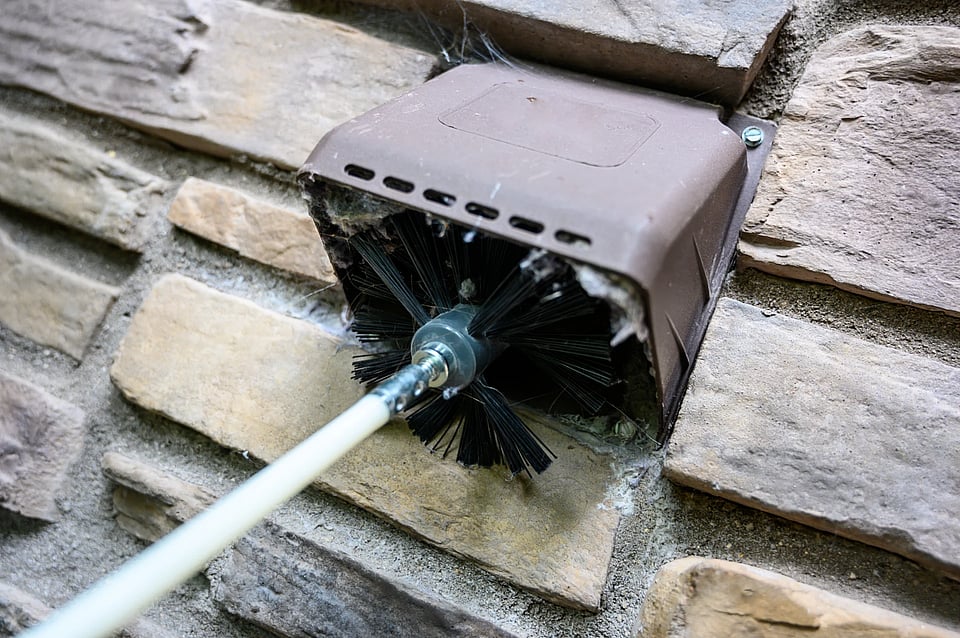 Adobe Stock image of a dryer vent cleaning brush clearing out link.