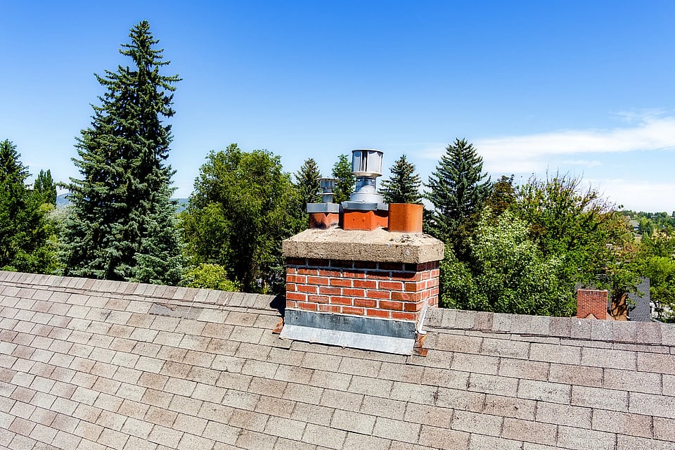Adobe Stock. image of a masonry chimney with multiple flues and caps.