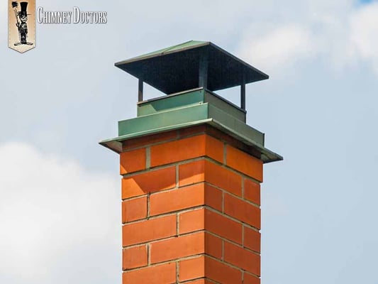 Brick chimney with a green chimney cap