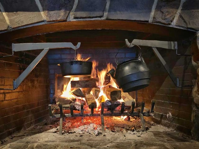 Stock image of cast iron pots sitting over a fireplace