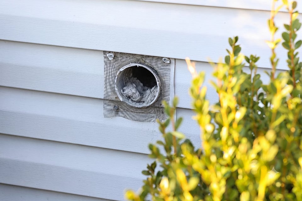 Stock photo of a dryer vent exhaust return with lint building up inside of it.