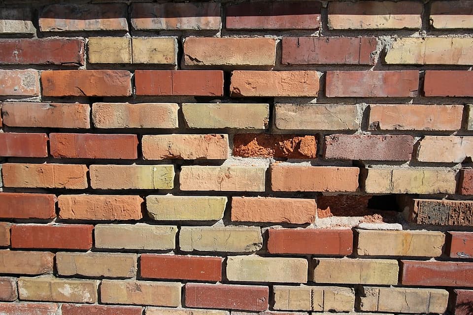 Weathered red brick chimney wall with crumbling mortar joints