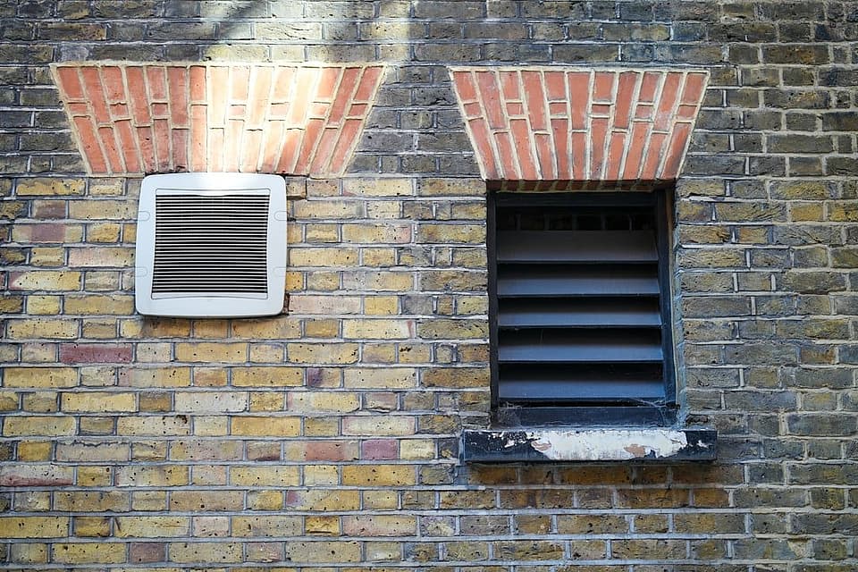 Exterior dryer vent louver set into a brick house wall